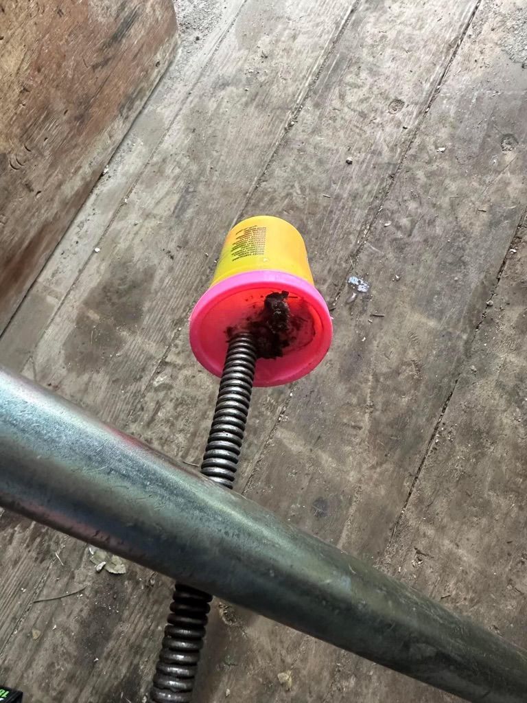 Yellow and pink wheel stop on a threaded rod against a weathered wooden floor