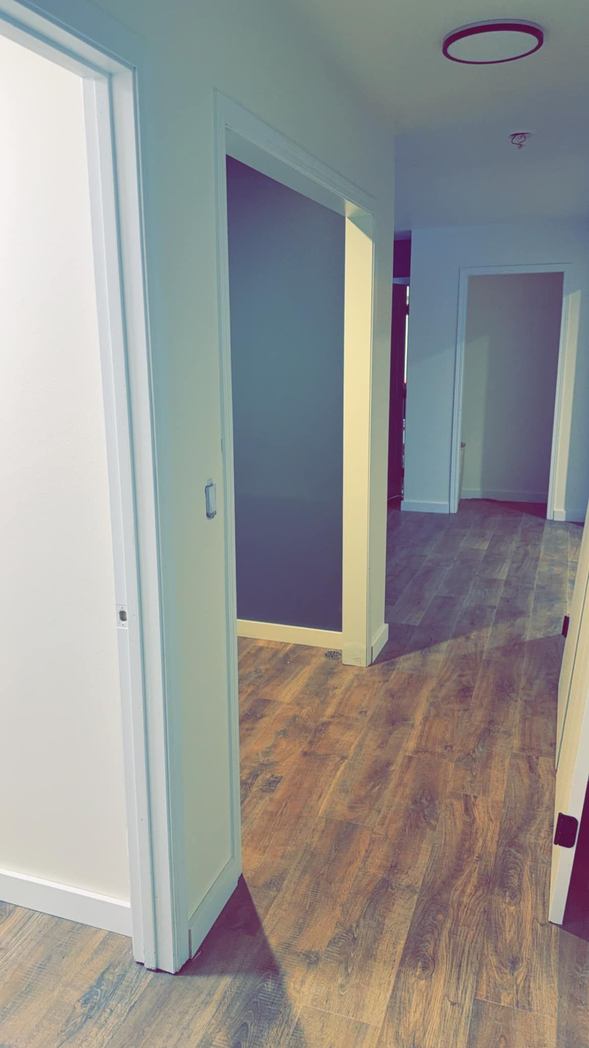 A hallway with wooden floors and white walls in a house.