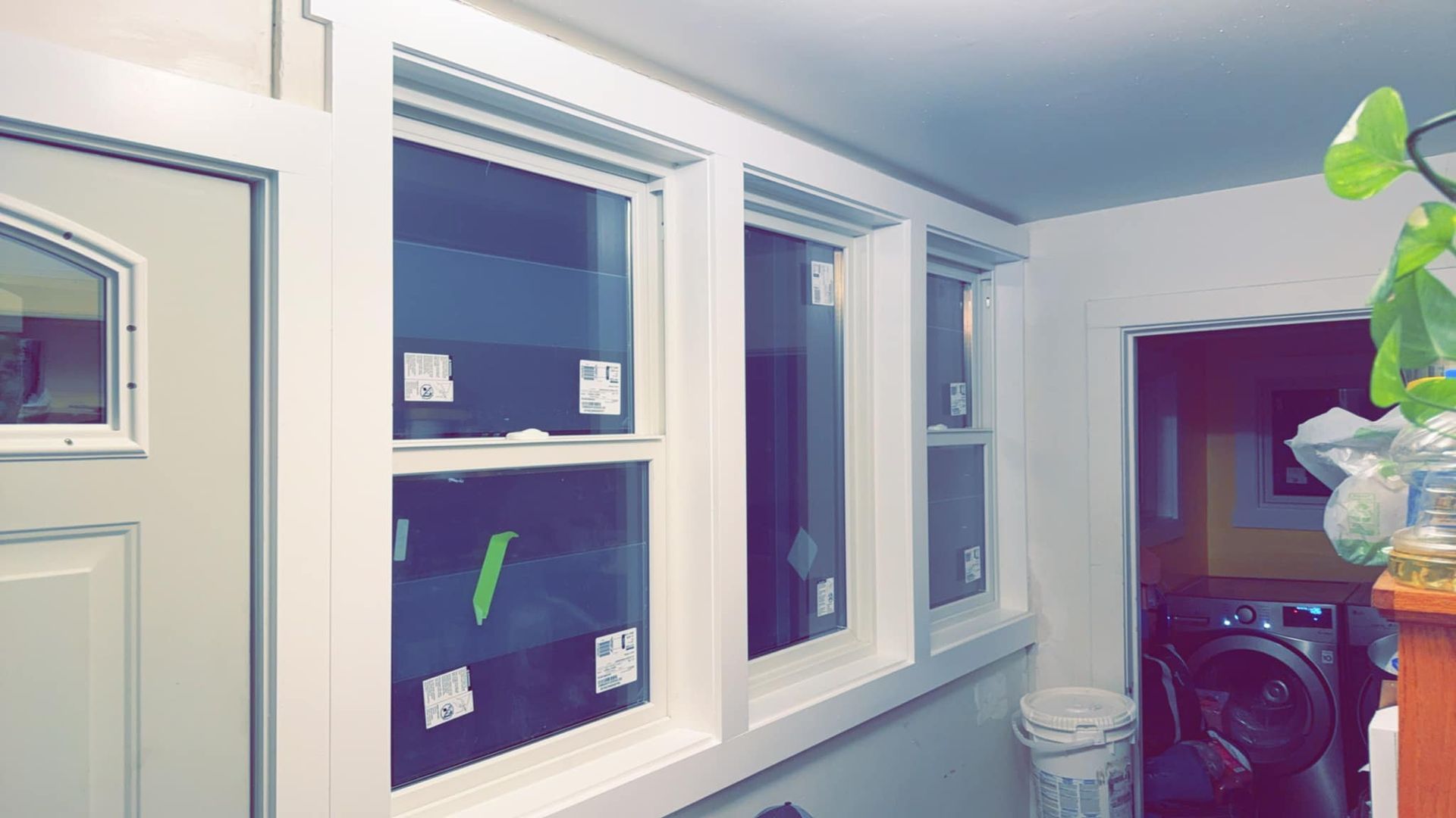A laundry room with a washer and dryer and a lot of windows.