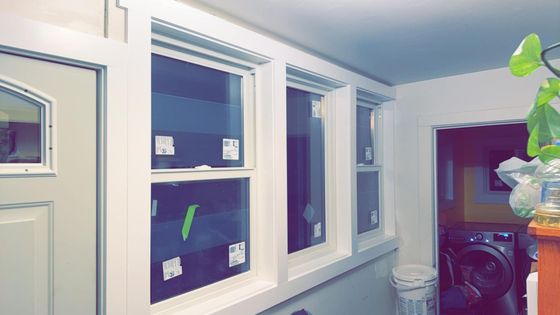 A laundry room with a washer and dryer and a lot of windows.
