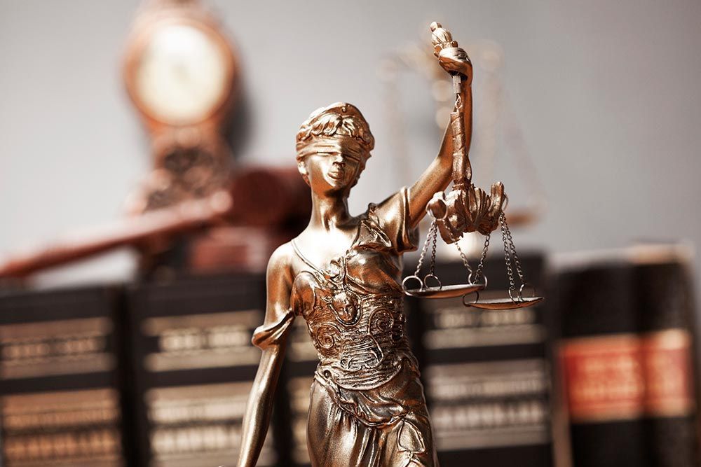Lady Justice statue in front of law books and a gavel, symbolizing the legal system
