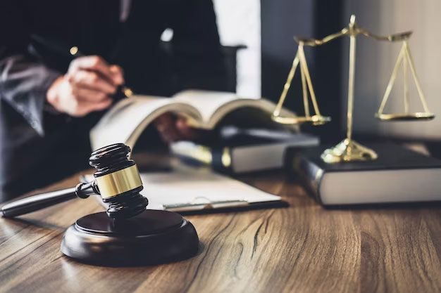 Lawyer’s desk with gavel, open law book, and gold scales of justice