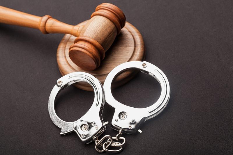 Handcuffs and a wooden gavel on a dark surface, suggesting law and justice