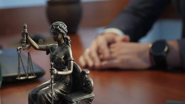 Bronze Lady Justice statue on a desk with blurred hands in the background
