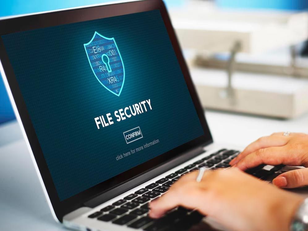 Hands typing on laptop showing “File Security” shield icon on screen