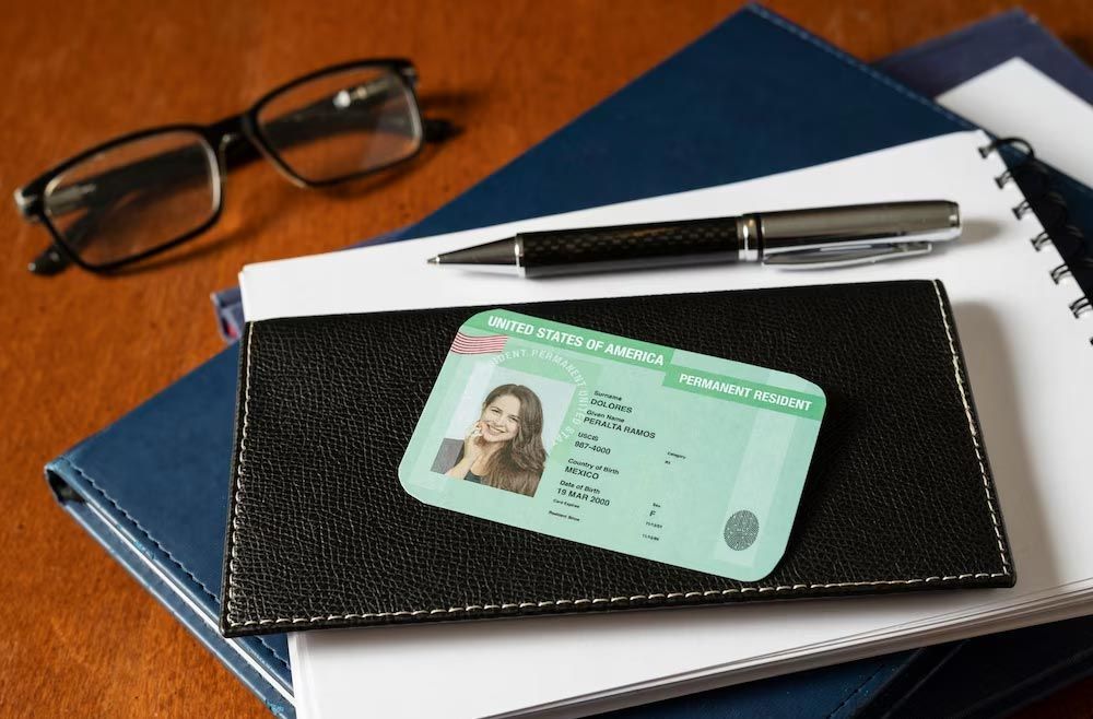 Wallet with ID card on notebooks beside glasses and a pen on a desk