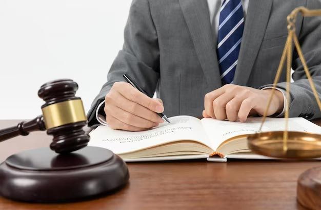 Lawyer writing at a desk with a gavel and scales of justice nearby