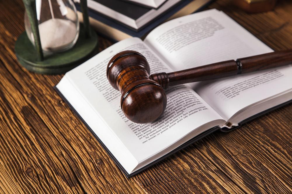 Gavel resting on an open law book on a wooden desk