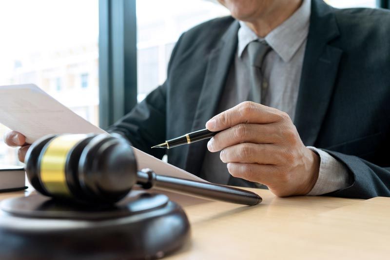 Lawyer holding a pen beside a gavel on a desk, reviewing papers in an office