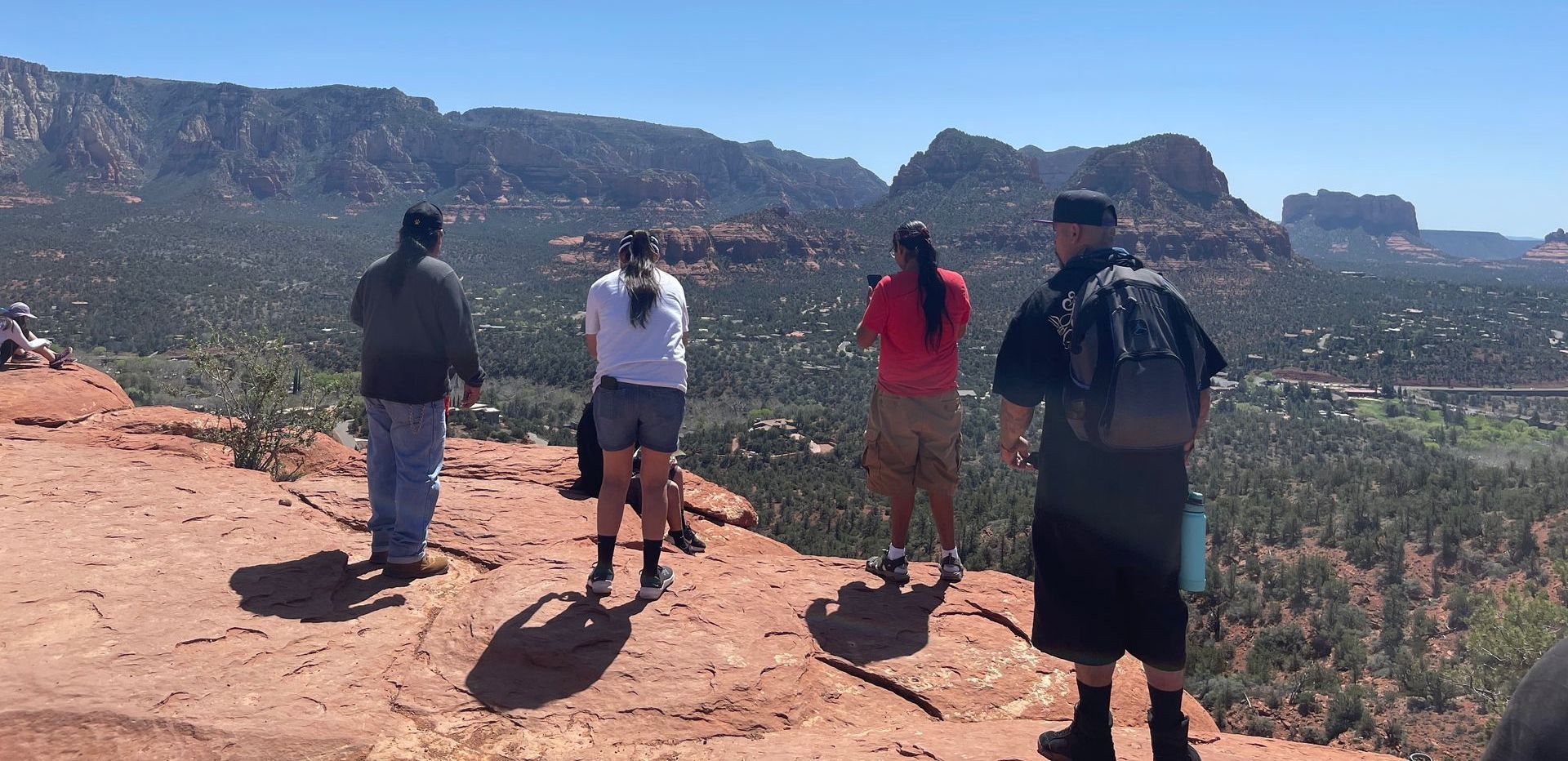 A group of people are standing on top of a rocky hill overlooking a valley.