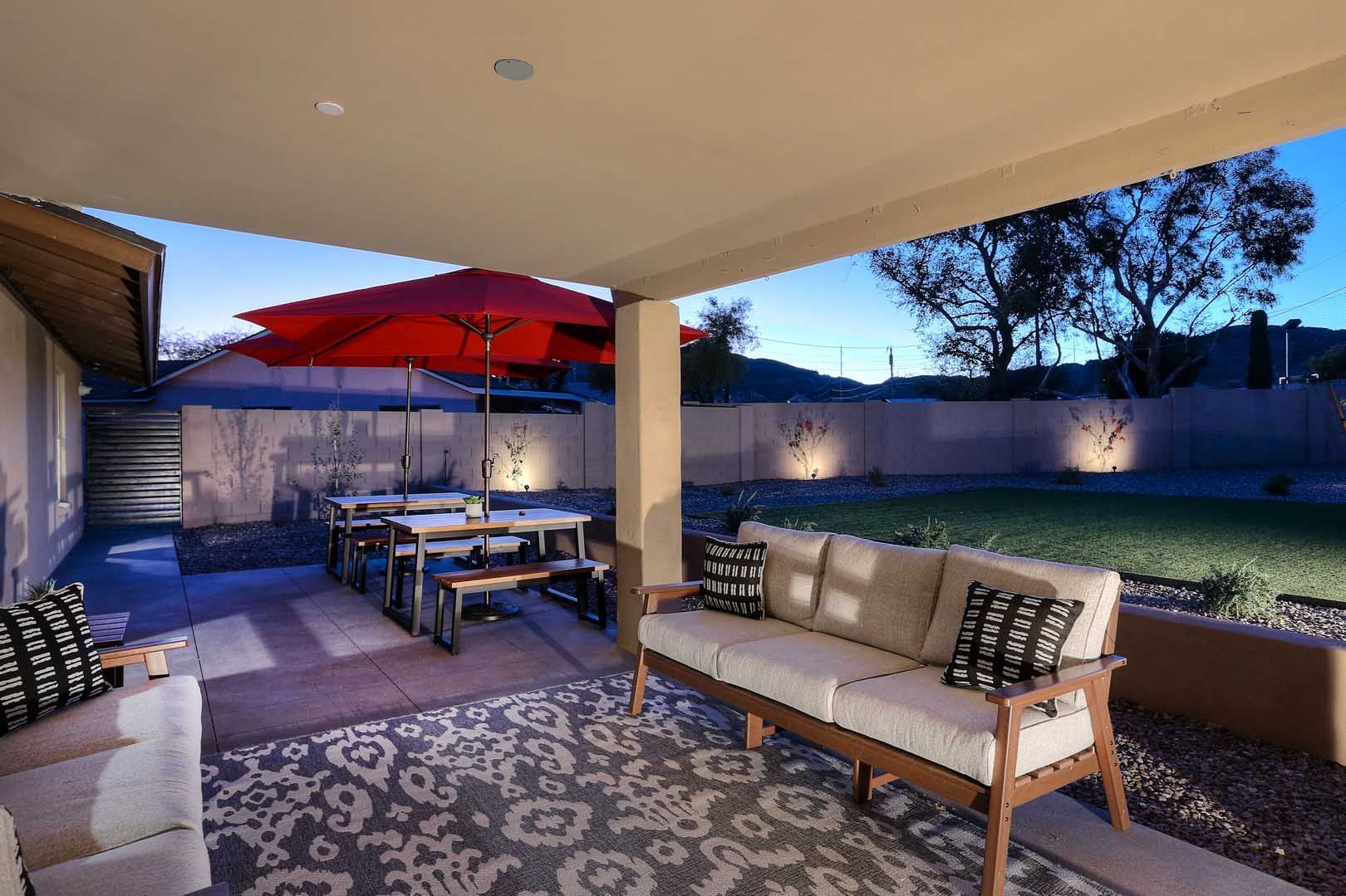 A patio with a couch , chairs , tables and umbrellas