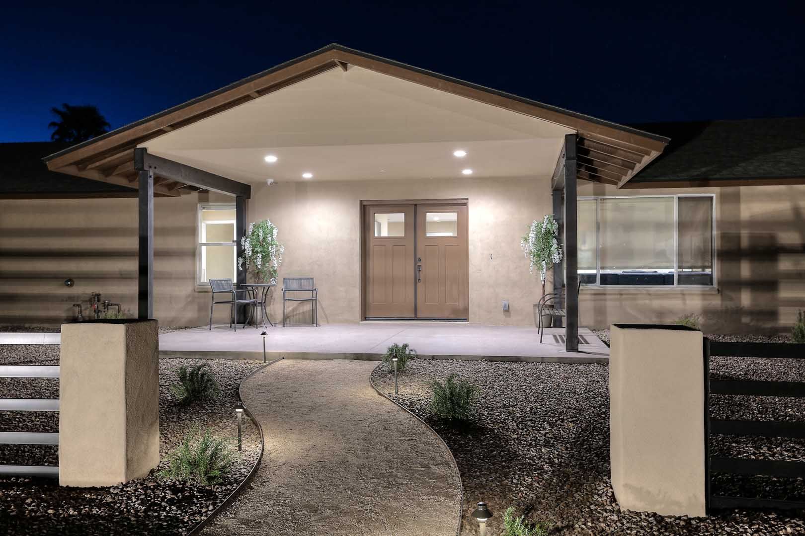 A house with a porch and a walkway leading to it at night