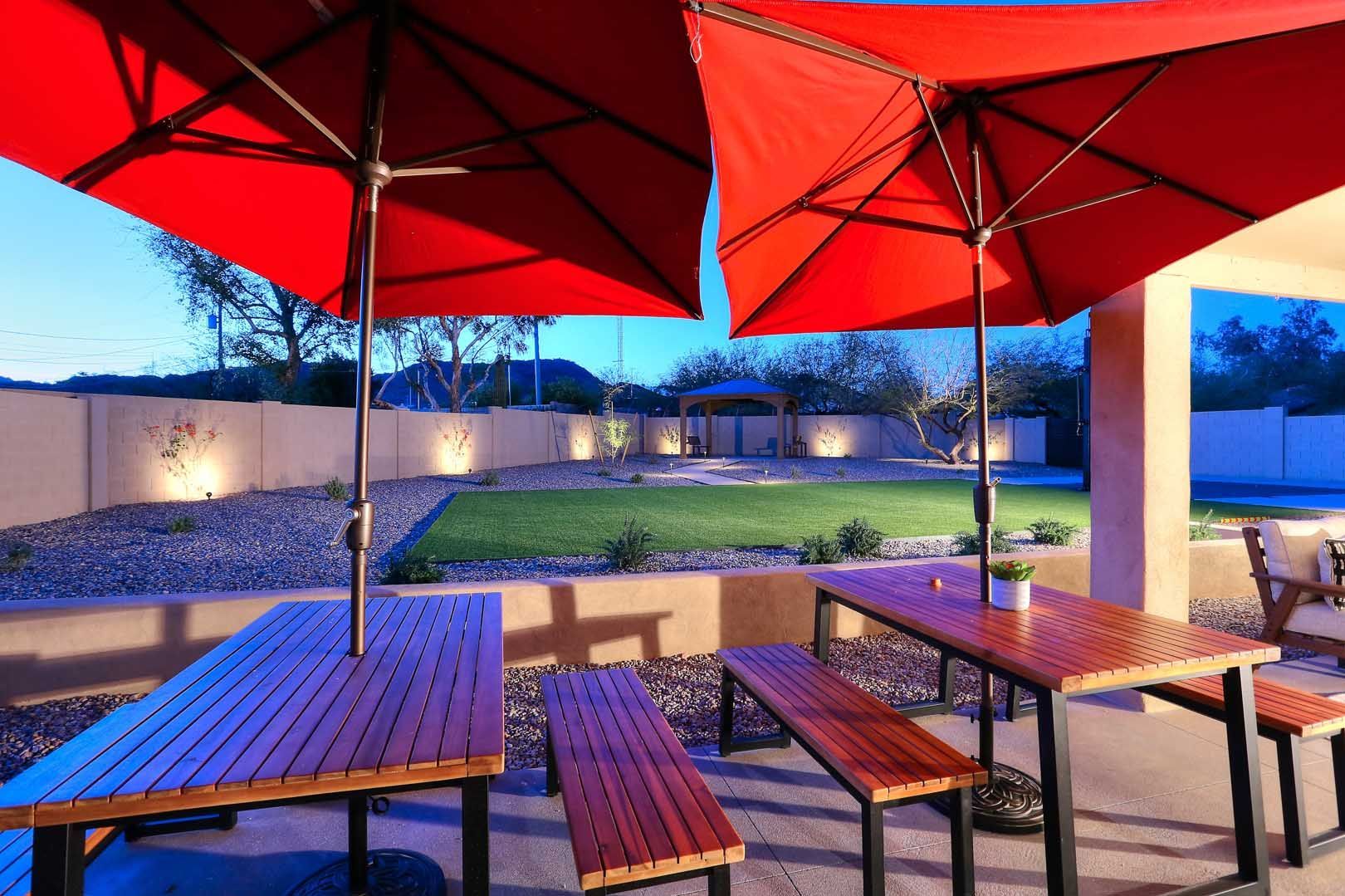 A patio with tables and benches under red umbrellas