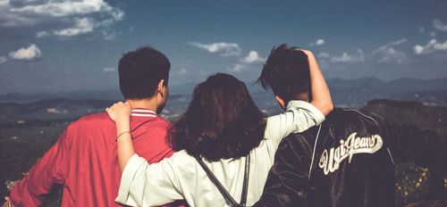 A group of young people are standing on top of a hill.