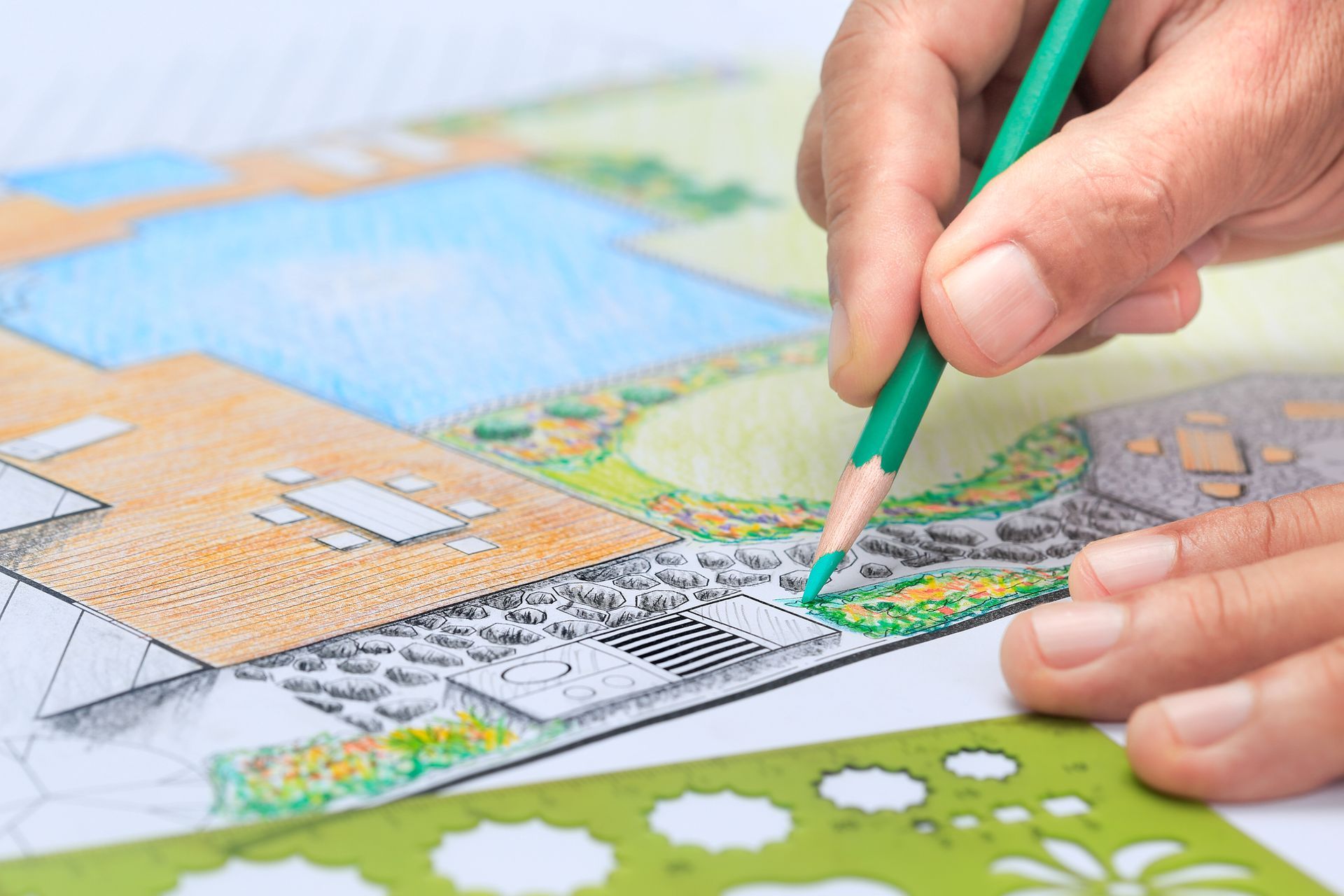 Close-up of landscape design service plan with garden layout, pool, and patio area being sketched.
