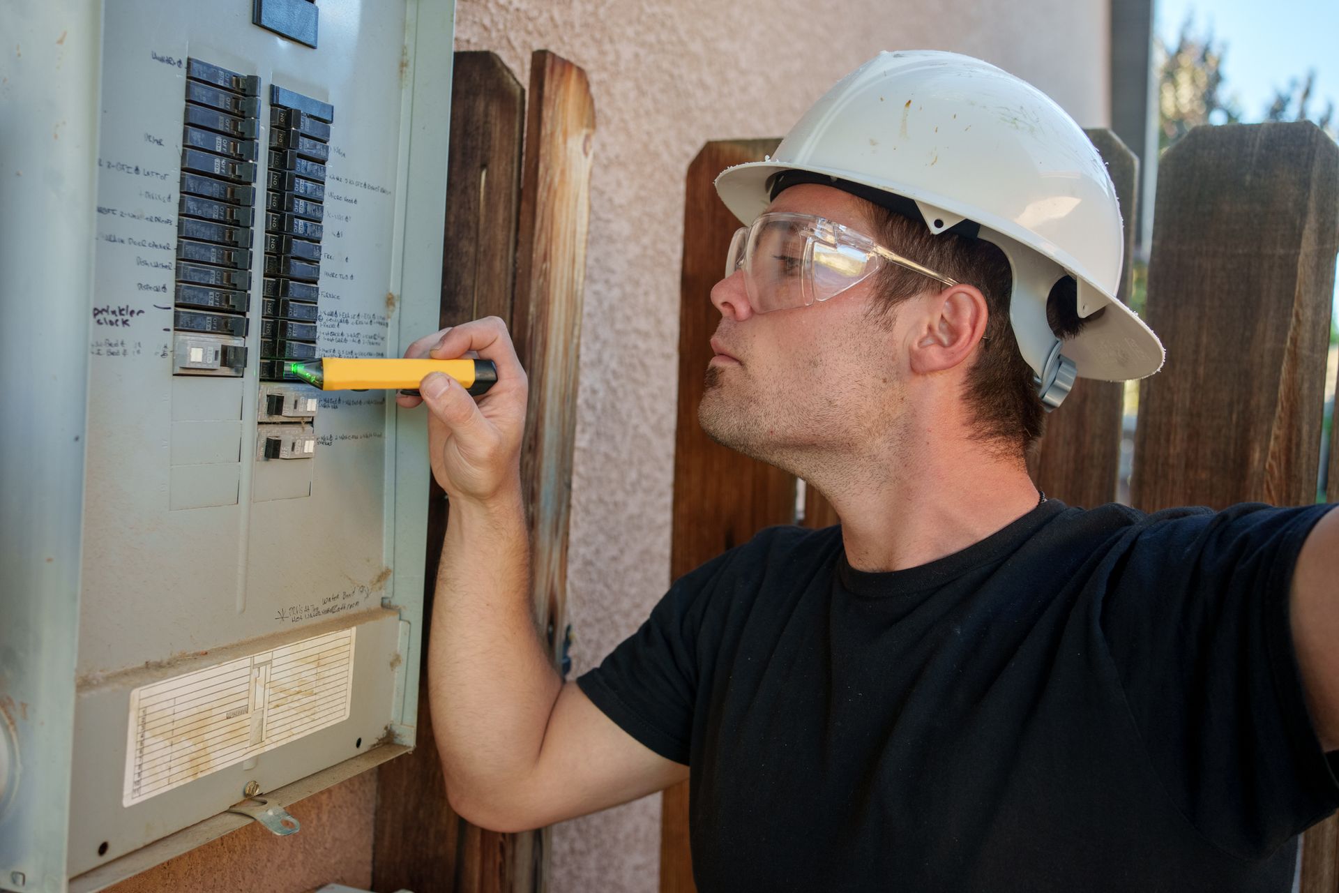 A residential electrician wearing glasses inspects a breaker panel, ensuring safety & compliance. A residential electrician wearing glasses inspects a breaker panel, ensuring safety & compliance.