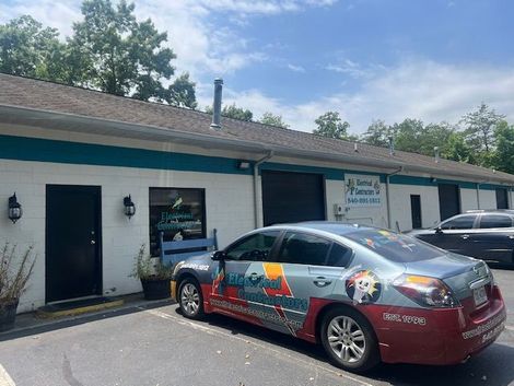 Client's Office - Veterans Affairs in Fredericksburg, VA Exterior of a business with a car displaying business branding parked in front. Building is white with teal accents.