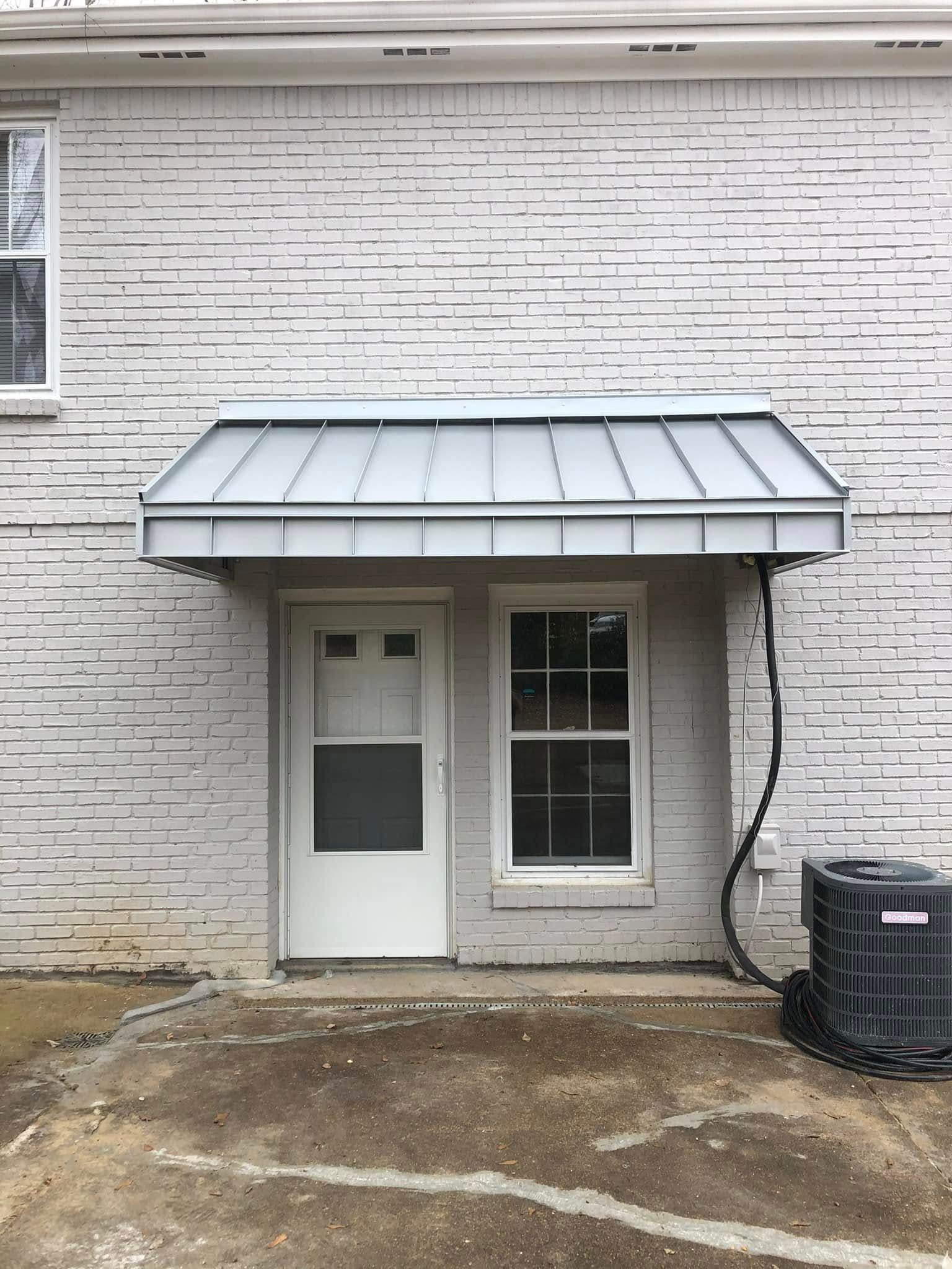 A white brick building with a canopy over the door