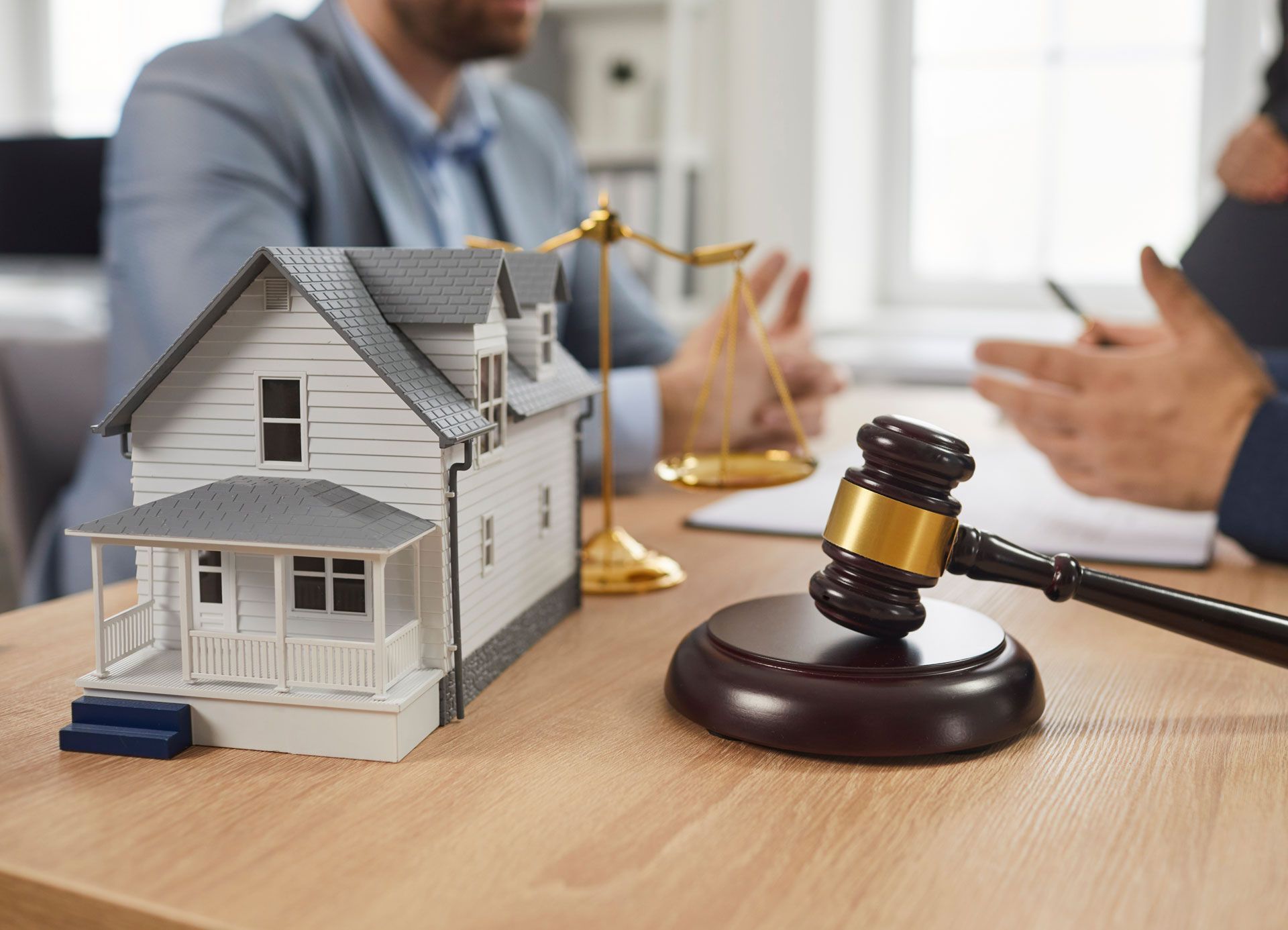 A man is sitting at a table with a model house and a gavel