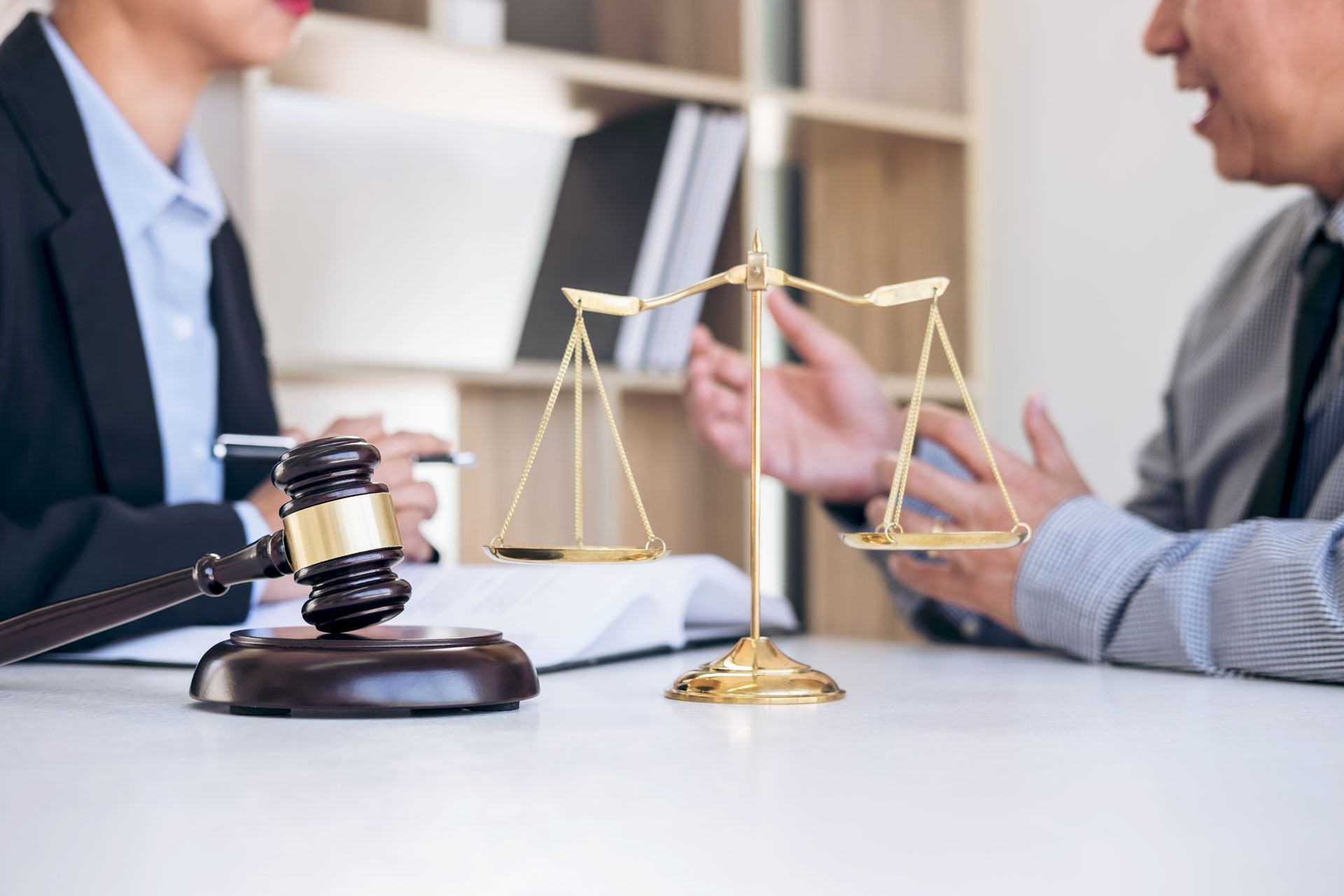 A man and a woman are sitting at a table with a gavel and scales of justice