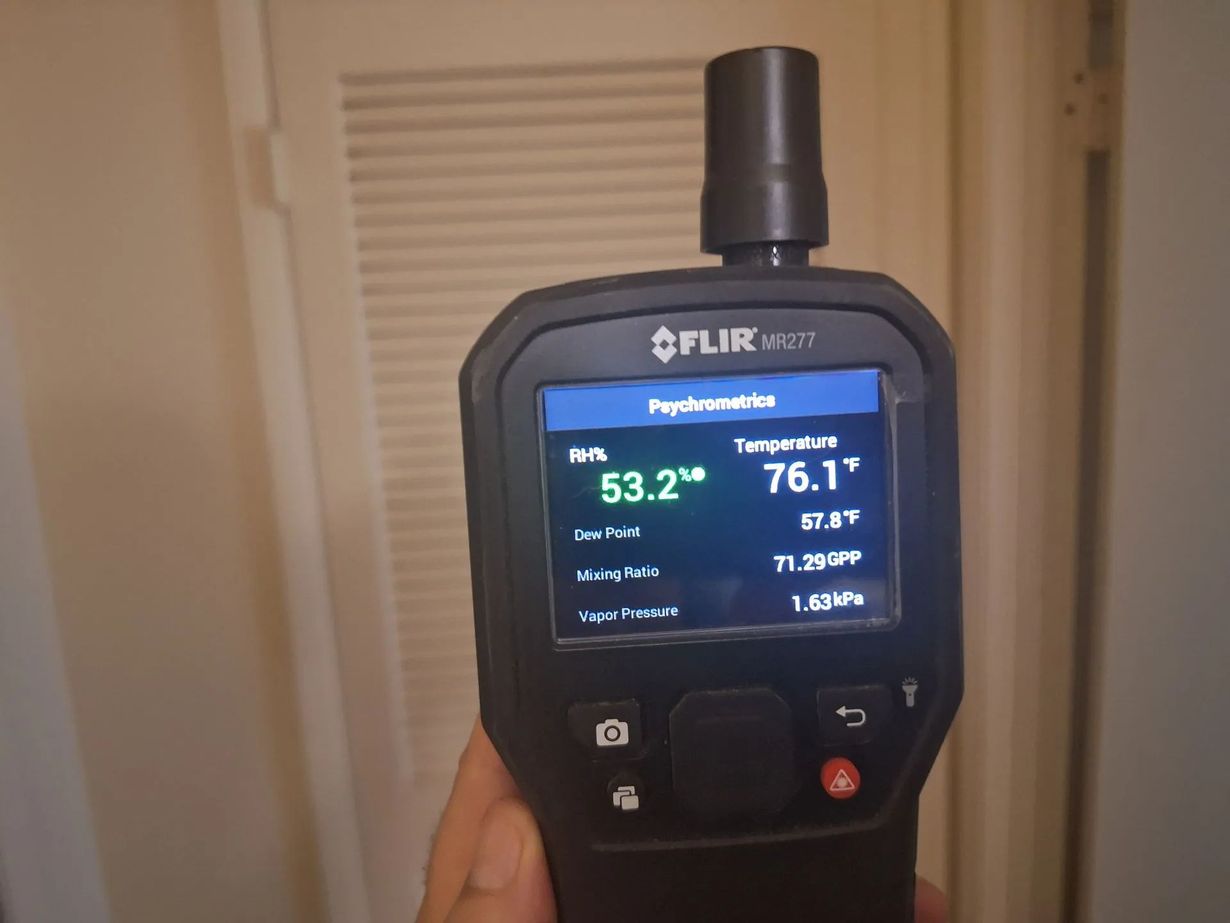 Handheld FLIR moisture meter screen showing air temperature of 76.1°F and relative humidity of 53.2%.