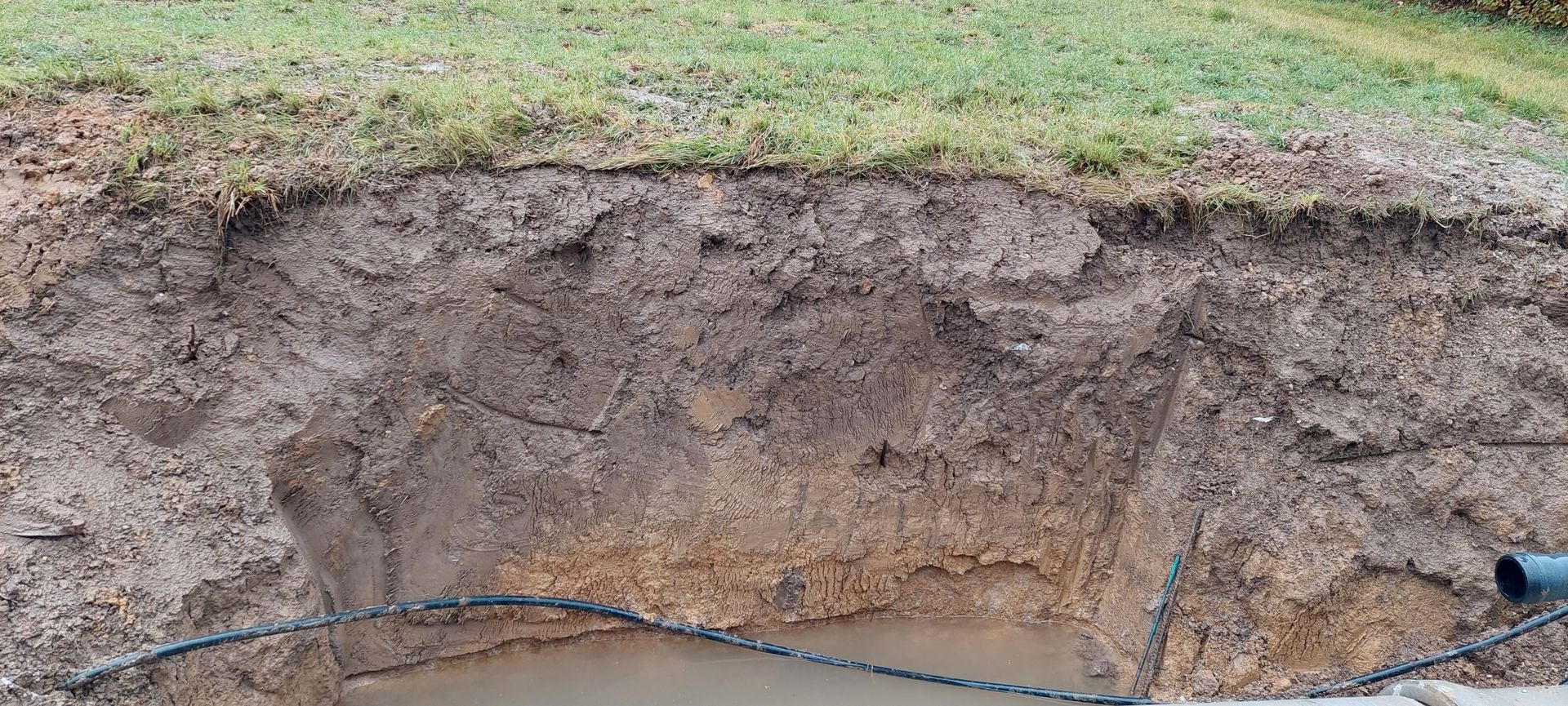Einschnitt in den Boden an einer Baustelle. Mehr als 50 cm dunkler fruchtbarer Oberboden auf einer Lehmschicht.