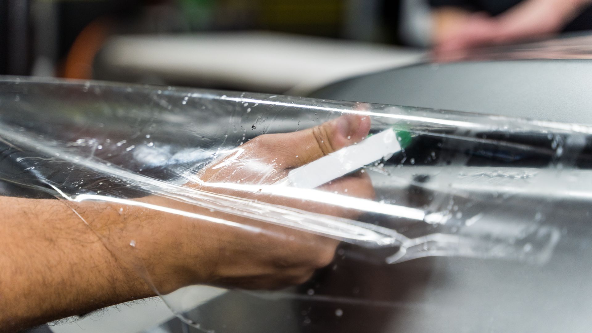 A person is holding a piece of plastic on a table.