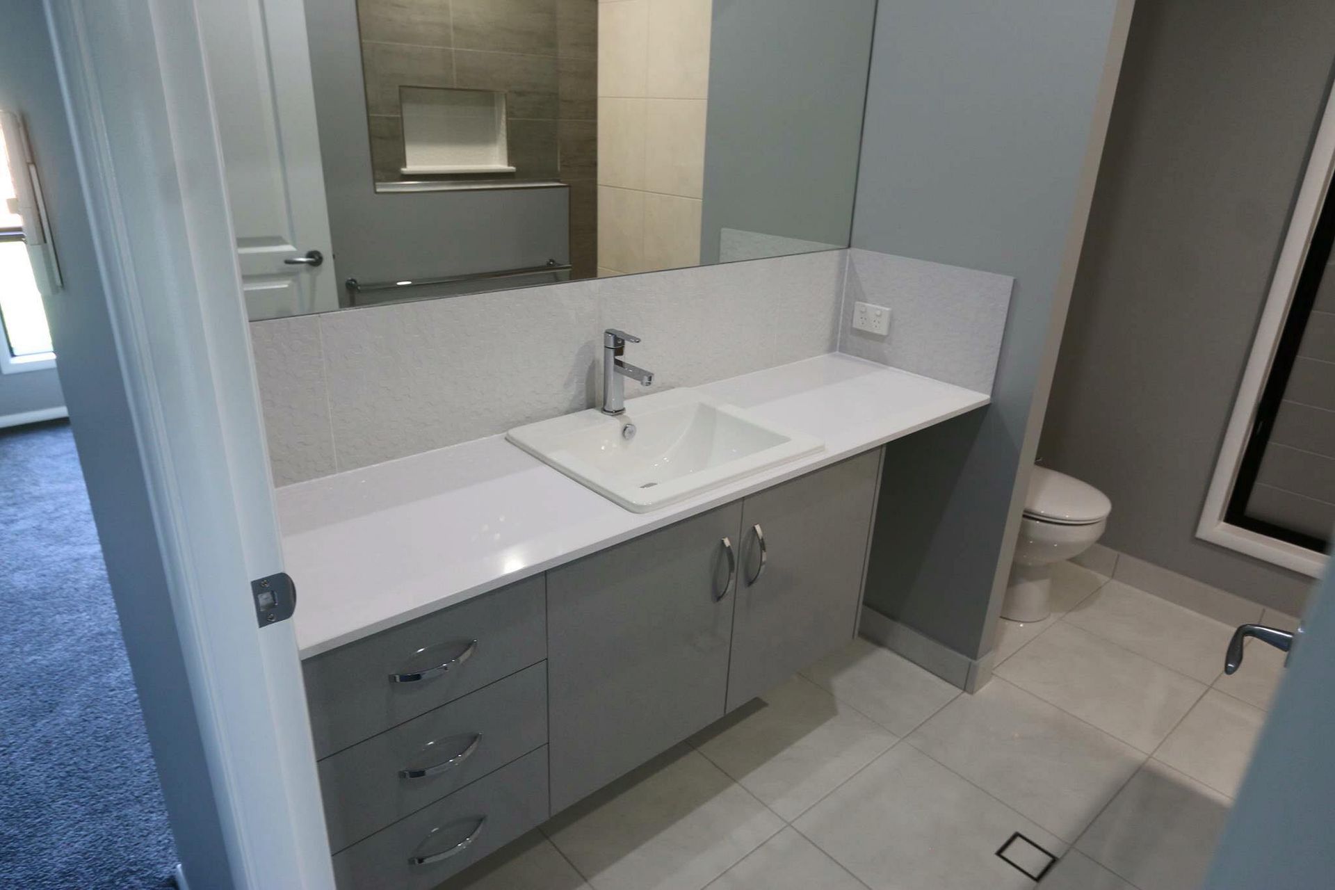 A Bathroom With a Sink, Toilet and Mirror — Ross Joinery Kitchens In Garbutt, QLD