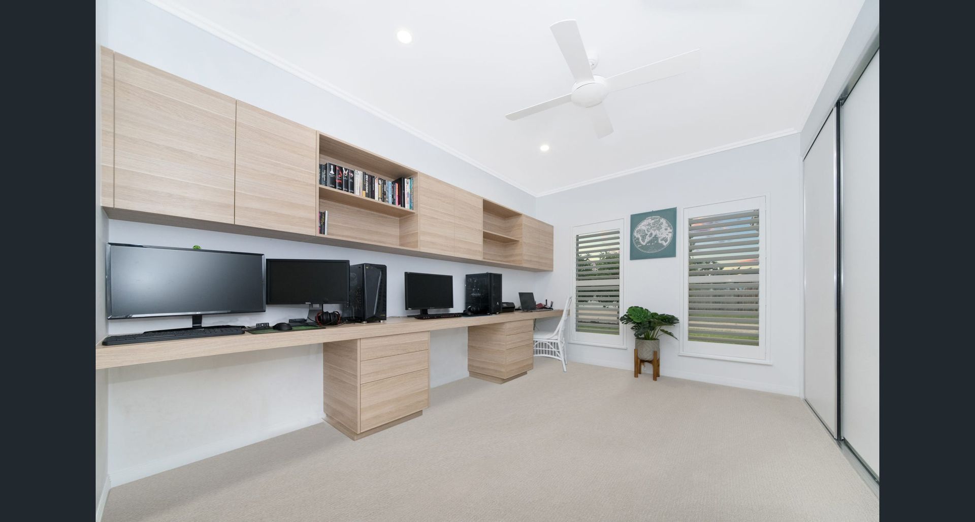 A computer desk with two monitors and a chair in a room — Ross Joinery Kitchens In Garbutt, QLD