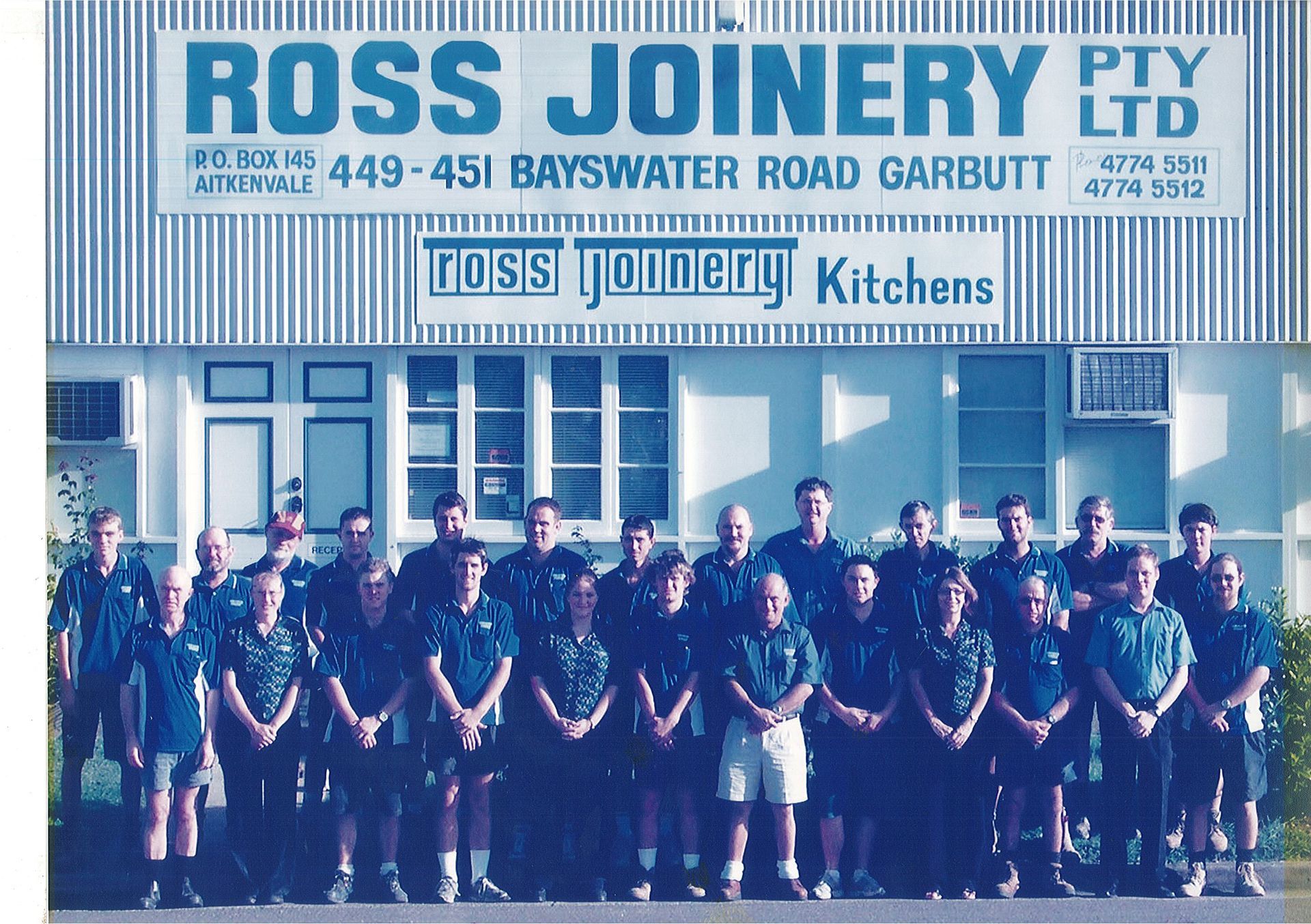 A Group of People Are Posing for a Picture in Front of a Ross Joinery Kitchens Building — Ross Joinery Kitchens In Garbutt, QLD