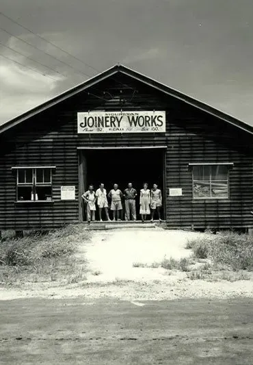 A Group of People Are Standing in Front of a Building That Says Joinery Works — Ross Joinery Kitchens In Garbutt, QLD