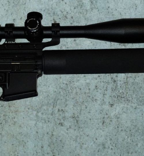 Black rifle with scope on a light speckled surface