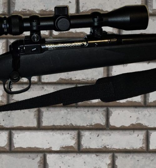 Black rifle scope and sling on a gun against a brick wall background