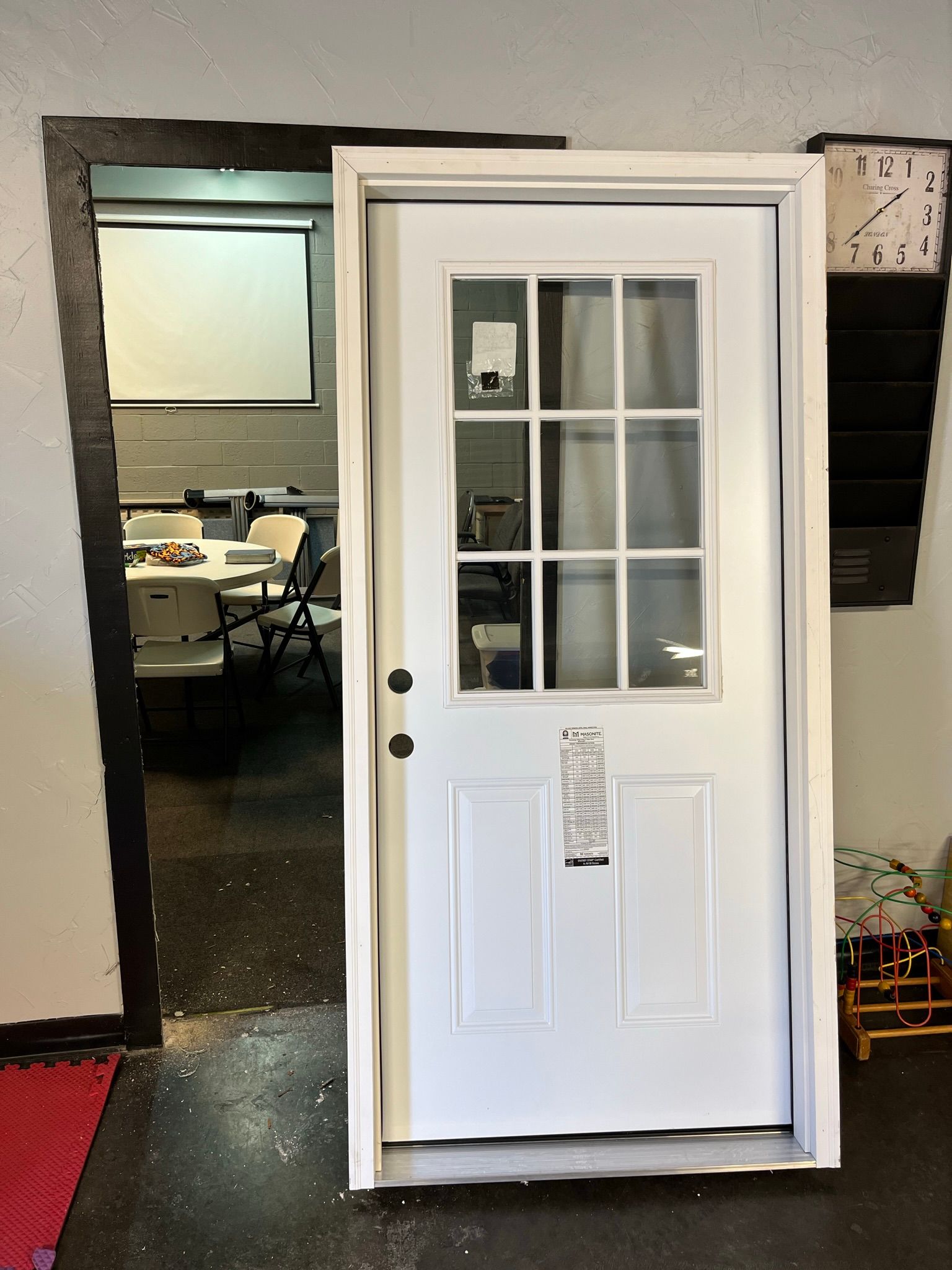 White door with glass pane, leading to a room with tables and chairs.