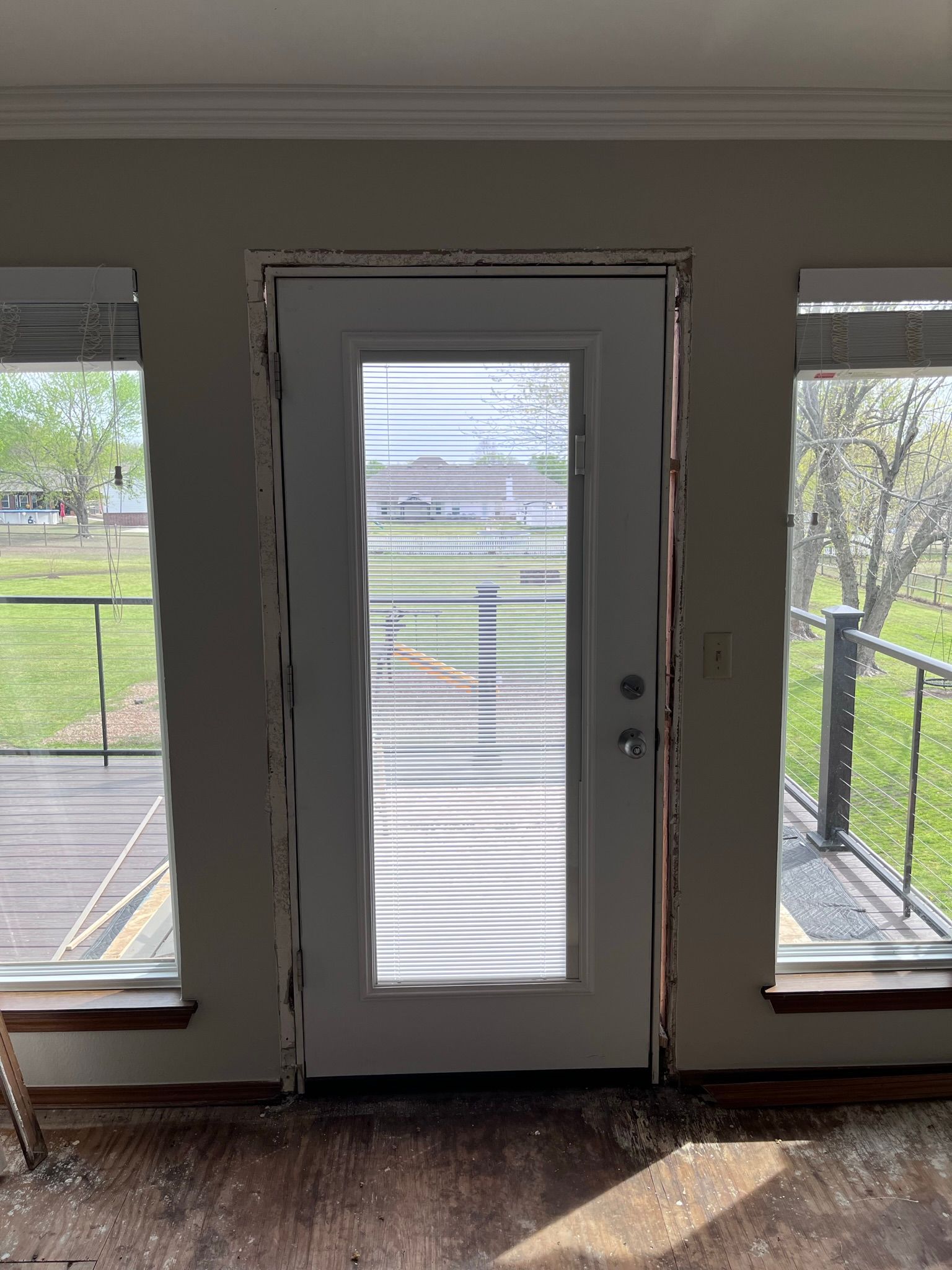 White exterior door between two windows, visible interior with stripped trim.