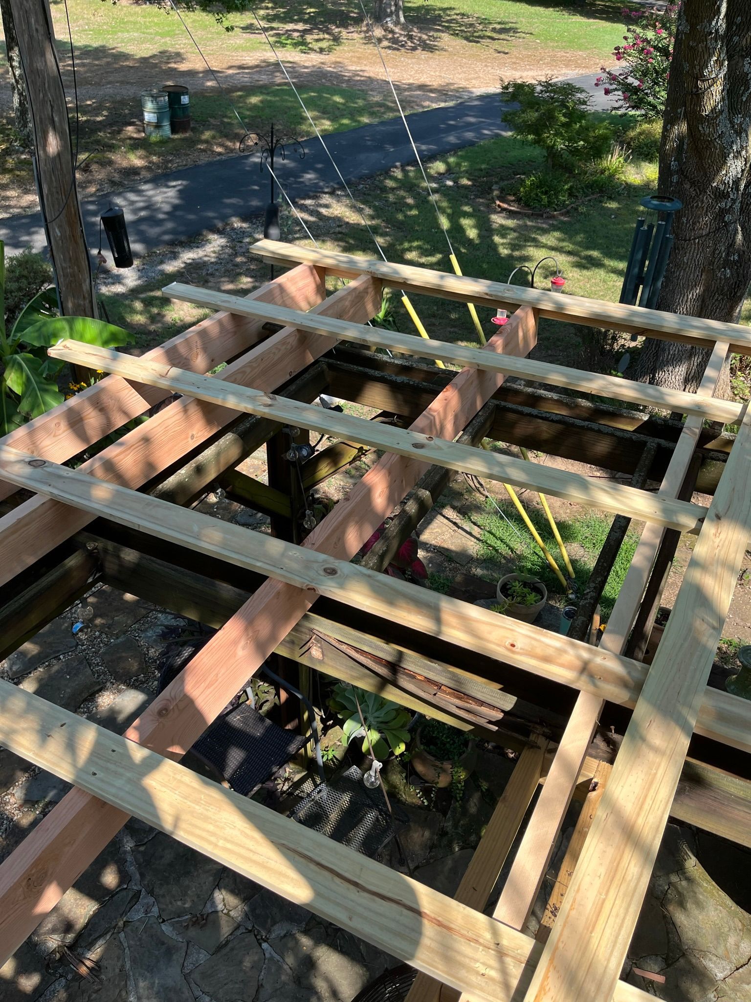 Wooden deck frame under construction outdoors with trees in background.