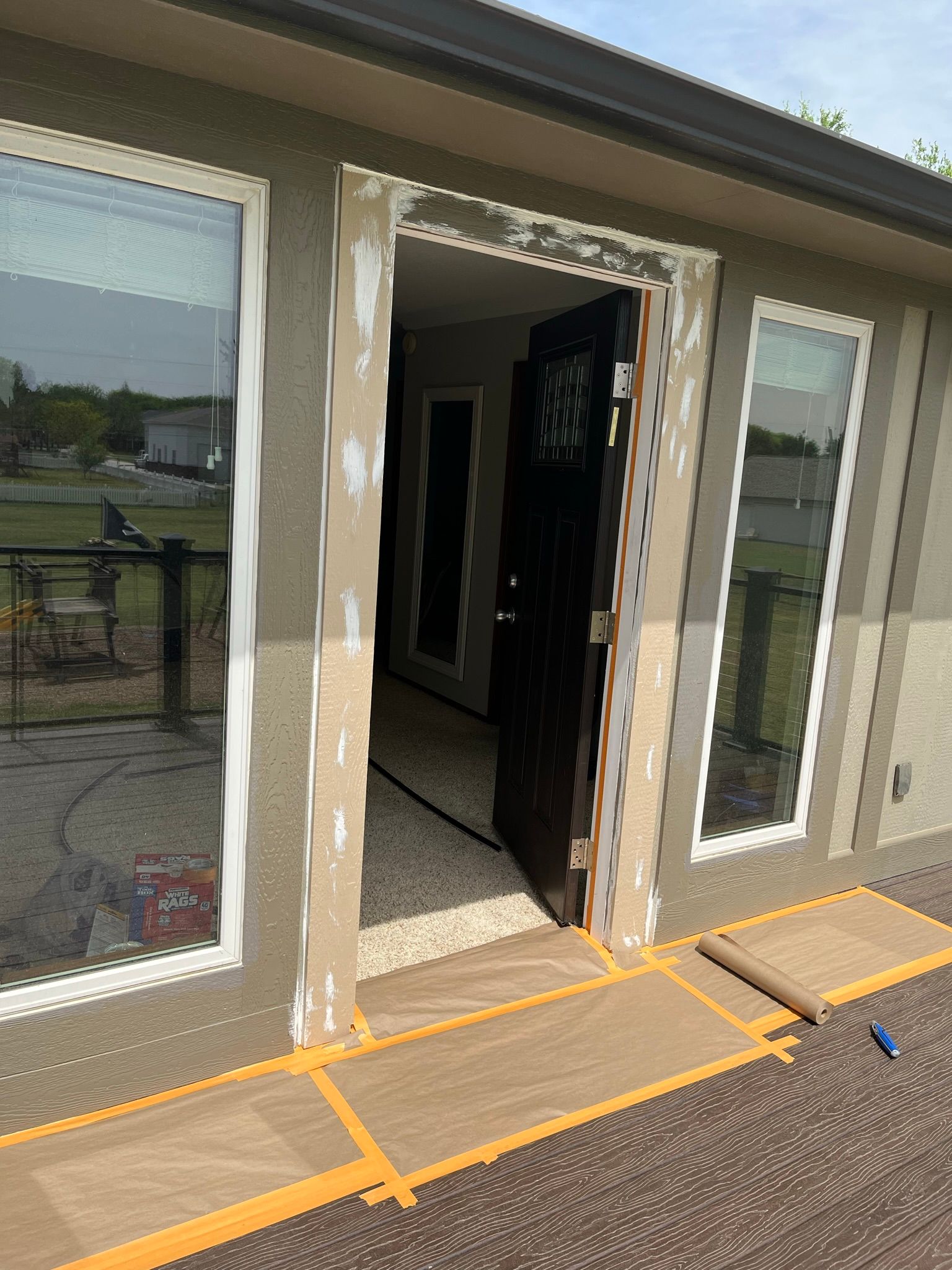 Exterior doorway with paint damage and protective mats on a deck.
