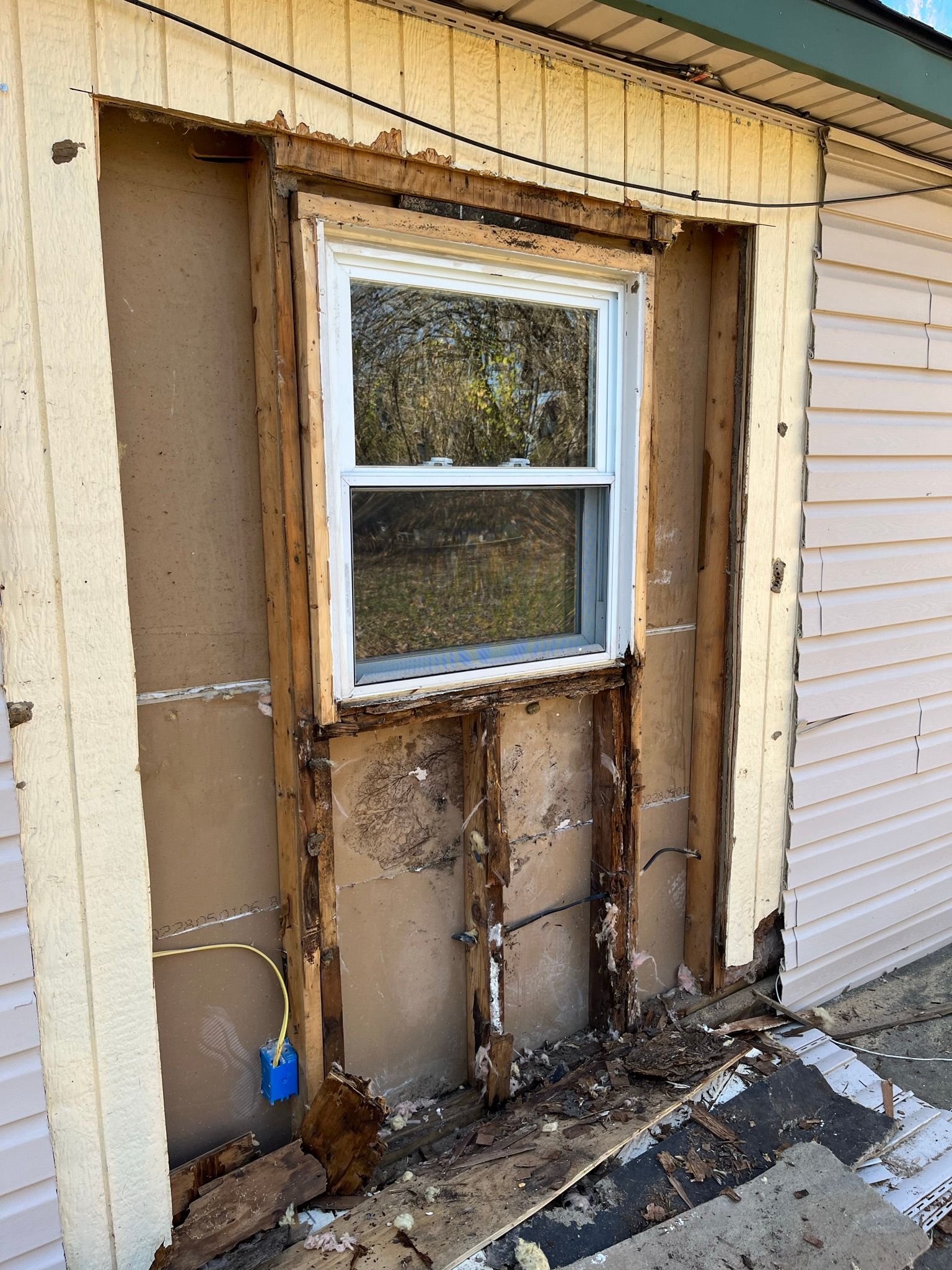 Exterior wall with window framed by exposed wood and insulation.