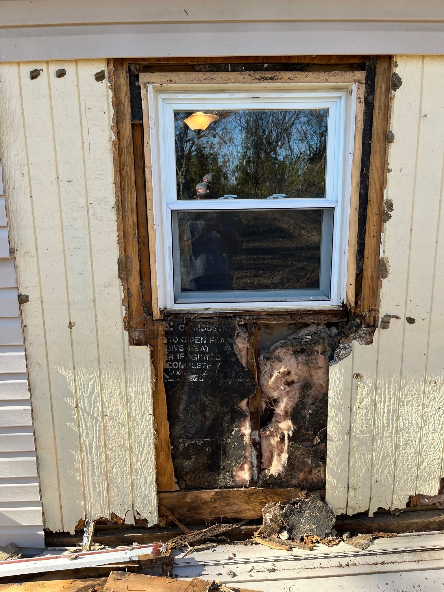 Window with rotted siding and exposed wood on a house exterior.