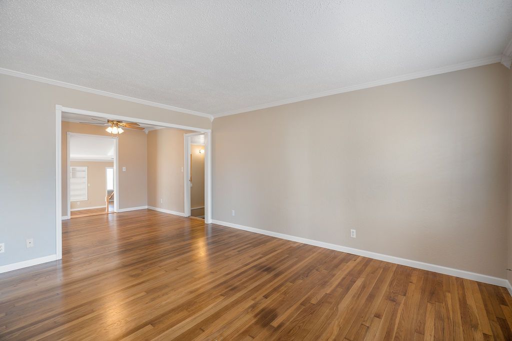 Empty living room with hardwood floors and beige walls.