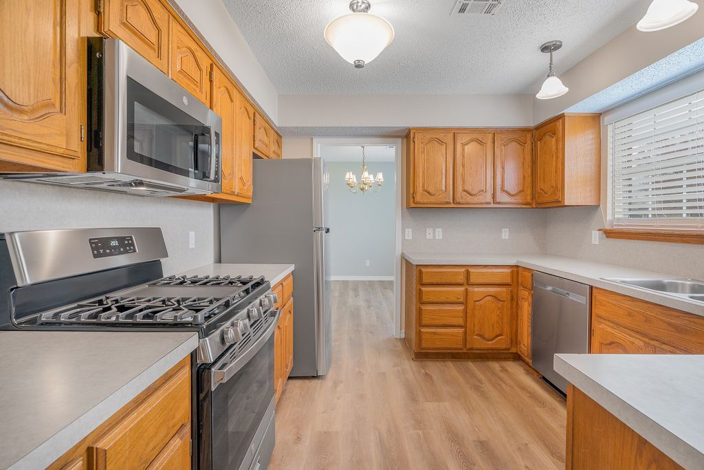 Kitchen with light wood cabinets, stainless steel appliances, and gray countertops.