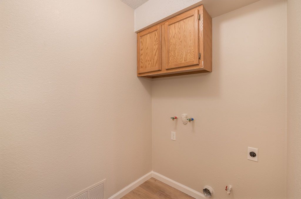 Laundry room with tan walls, cabinet, and water hookups.