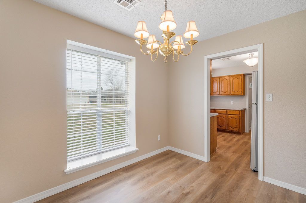 Dining room with a chandelier, window, and doorway to a kitchen.