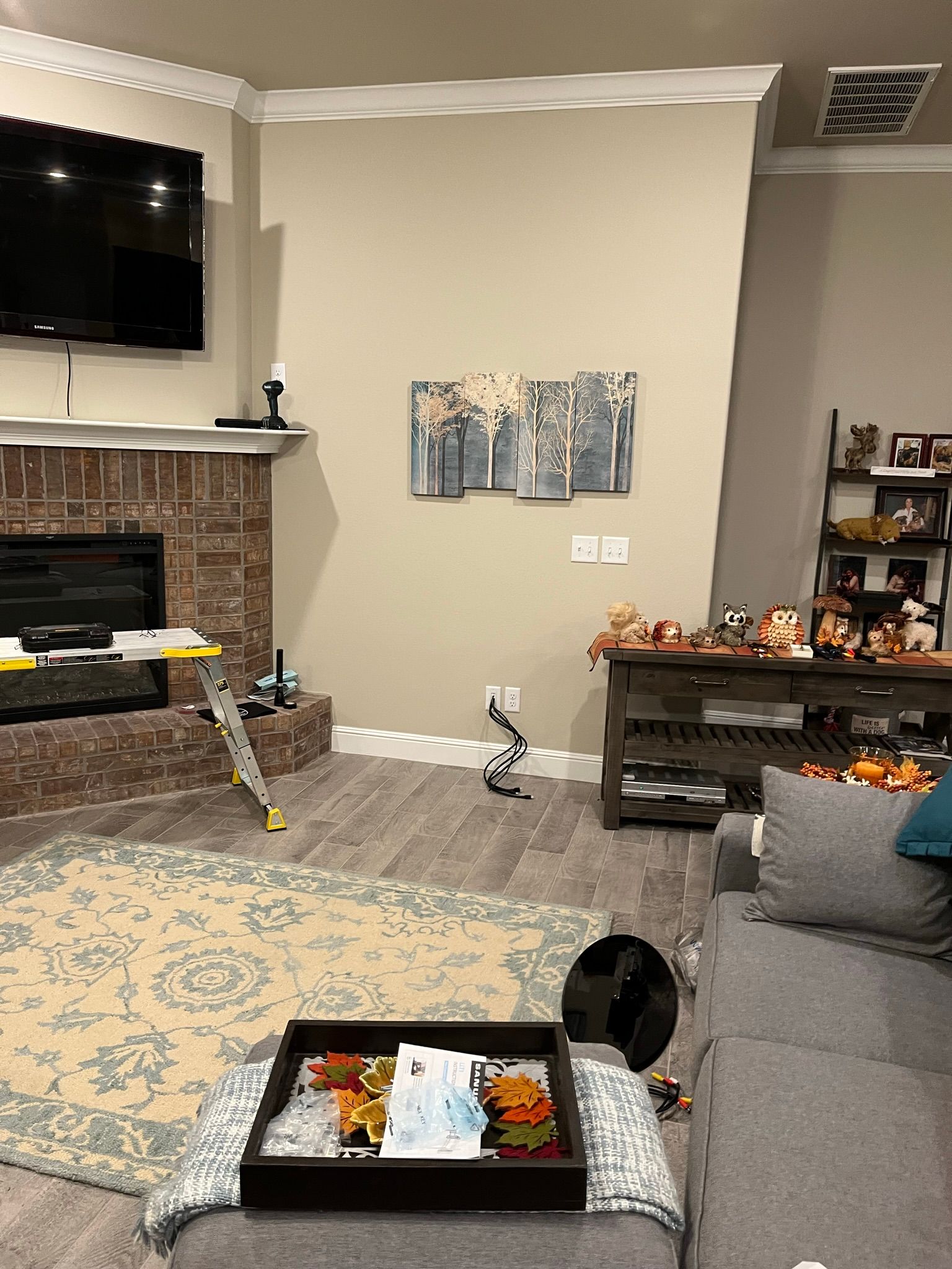 Living room with fireplace, TV, and artwork; includes rug, couch, and console table with decorations.