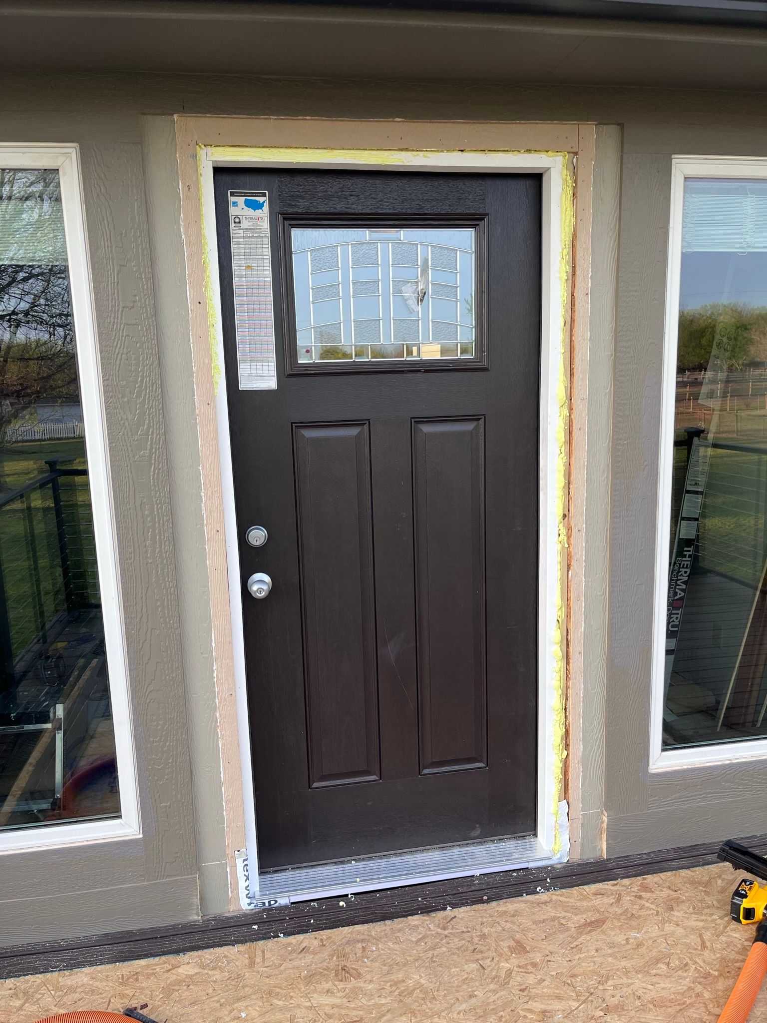 Brown front door with glass panel and sidelights under construction.