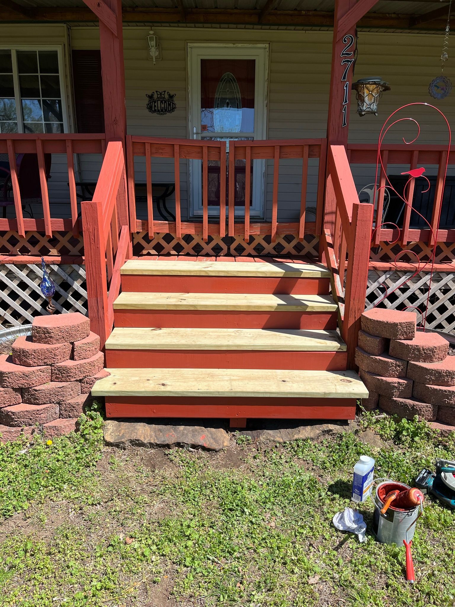 Red-painted wooden steps leading up to a porch with red railing and decorative brickwork.