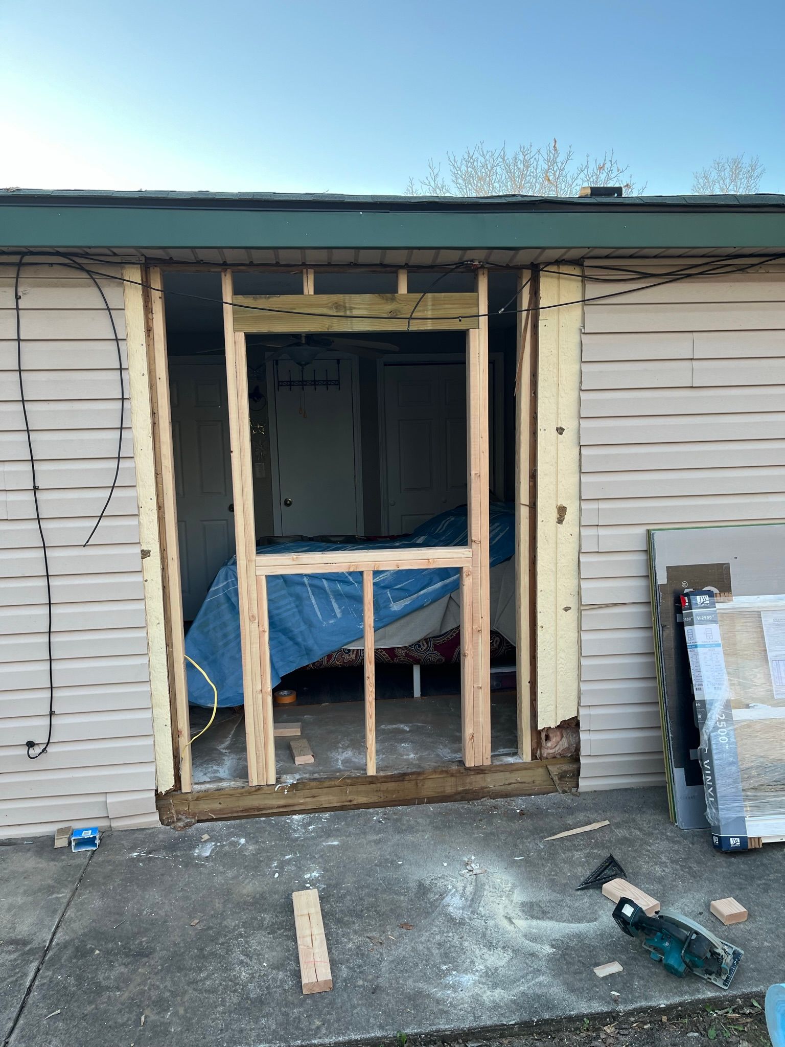 Exterior view of door frame construction, house siding visible.