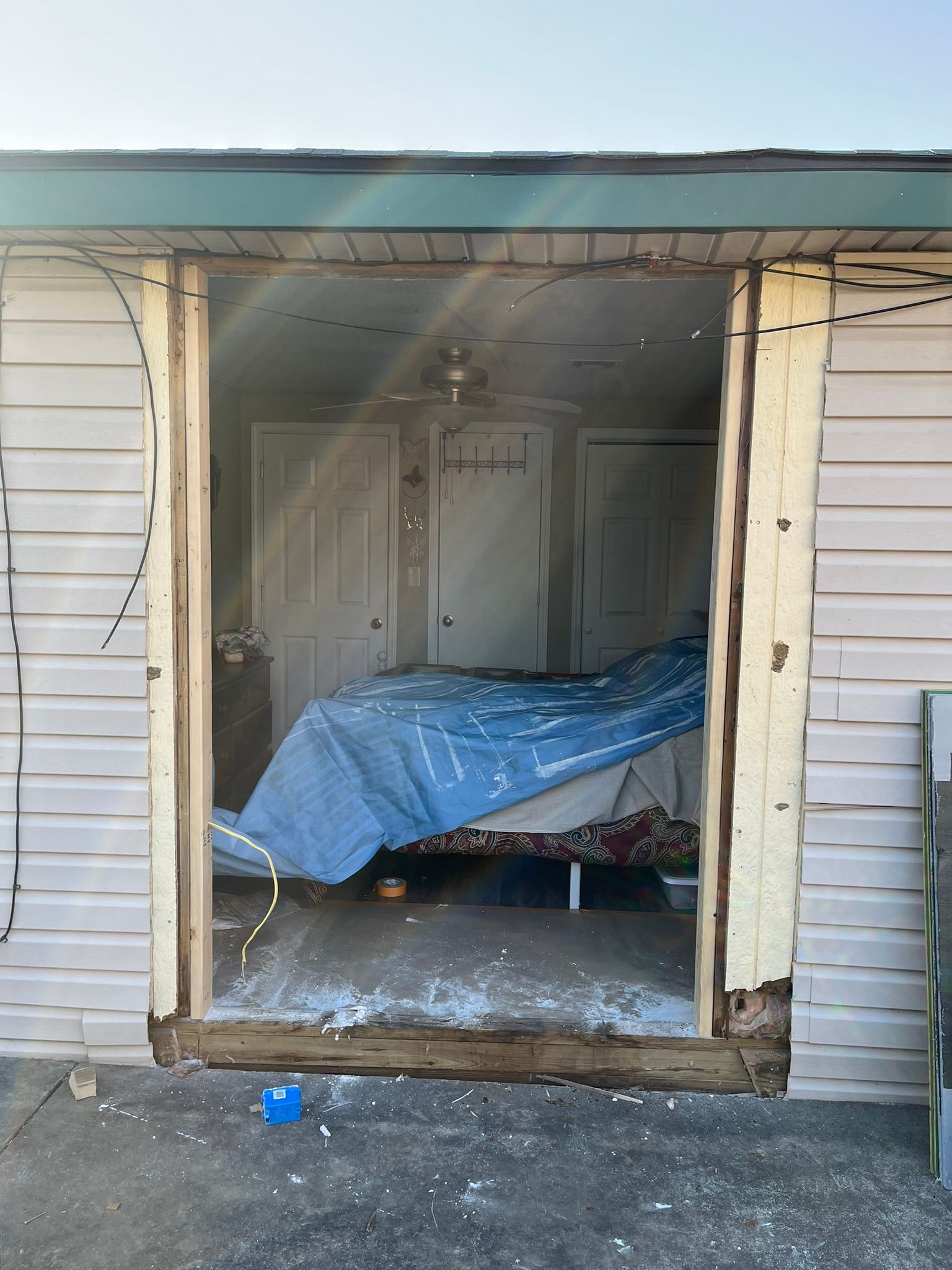 Exterior view through an open doorway, showing a bedroom with a covered bed.