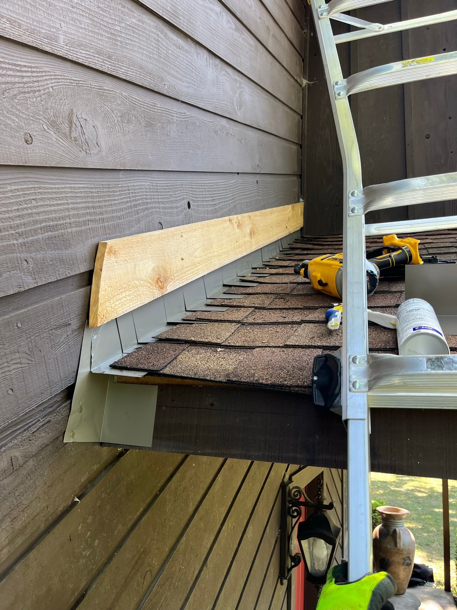 Roofing work: Installing flashing at roof edge, wood and metal construction; tools and ladder present.