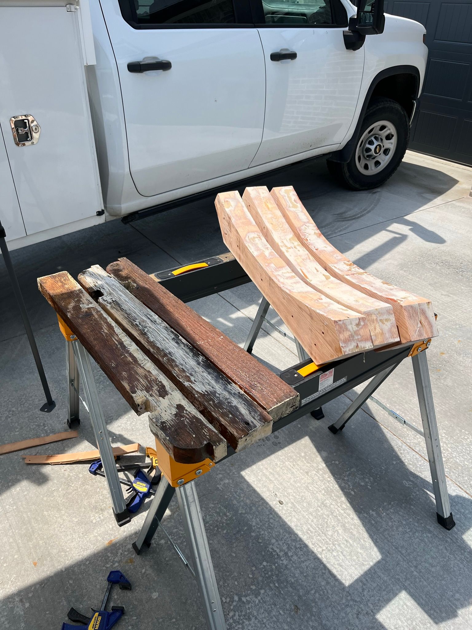 Work table with wood pieces, next to a white truck.